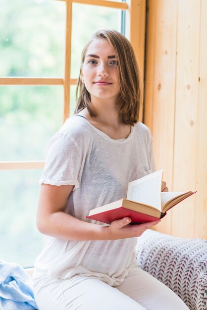 Portrait, de, jeune femme, tenue, livre, séance, devant, fenêtre