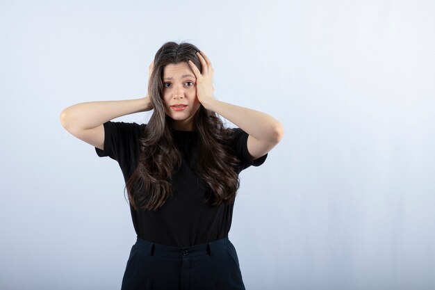 Portrait de jeune femme en tenue noire tenant sa tête.