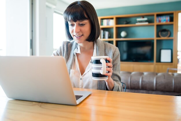 Portrait de jeune femme travaillant à domicile avec un ordinateur portable