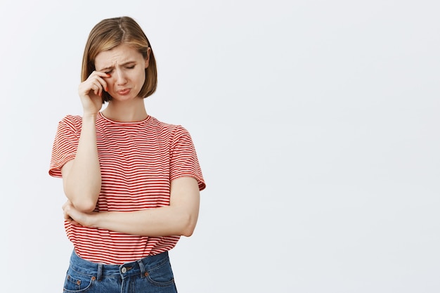 Portrait de jeune femme triste et affligée sanglotant, pleurant et essuyant ses larmes