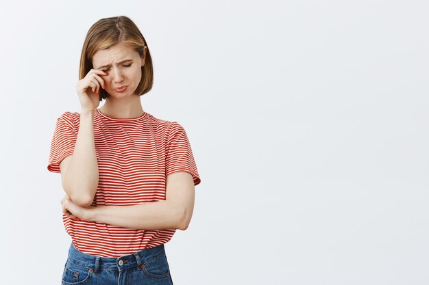 Portrait de jeune femme triste et affligée sanglotant, pleurant et essuyant ses larmes