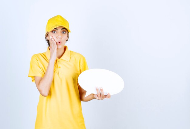 Portrait d'une jeune femme en uniforme jaune tenant une bulle vide vide.