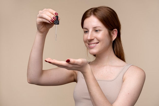 Portrait d'une jeune femme versant du sérum sur sa main