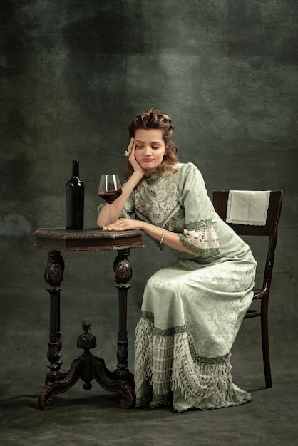 Photo gratuite portrait de jeune fille adorable à l'image d'une personne royale médiévale buvant du vin isolé sur fond sombre