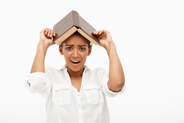 Portrait de jeune fille africaine avec livre sur mur blanc