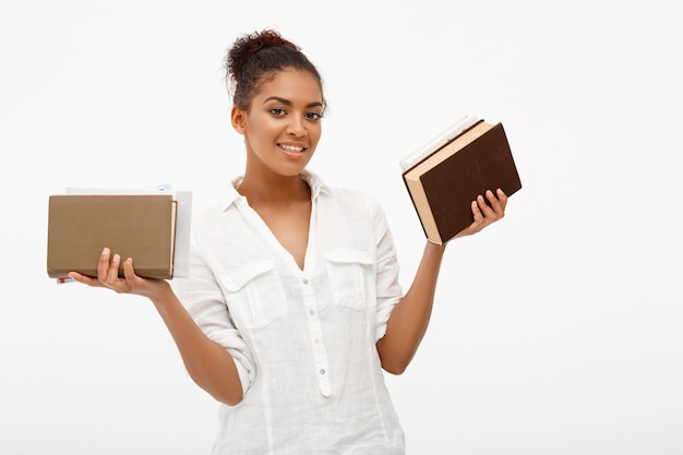 Photo gratuite portrait de jeune fille africaine avec des livres sur le mur blanc