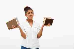 Photo gratuite portrait de jeune fille africaine avec des livres sur le mur blanc