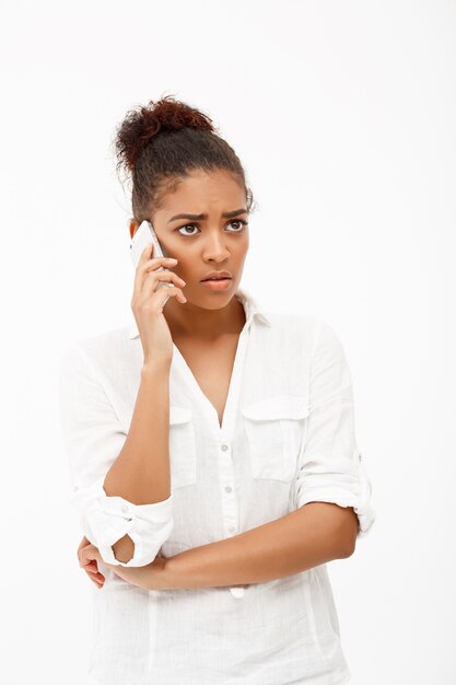 Portrait de jeune fille africaine parlant au téléphone sur wallck blanc