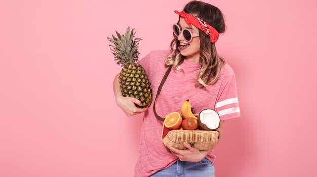 Portrait d'une jeune fille avec des aliments sains, des fruits, sur un mur rose