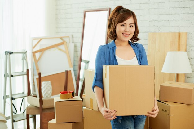 Portrait de jeune fille asiatique tenant une boîte en carton et regardant la caméra