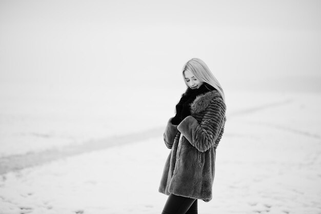 Portrait de jeune fille blonde élégance dans un fond de manteau de fourrure rivière brumeuse sur la glace d'hiver