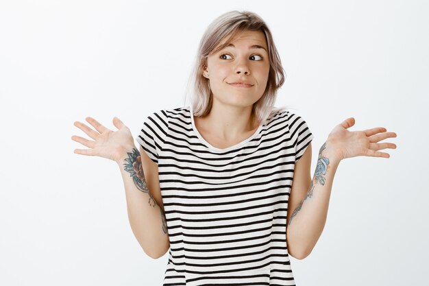 Portrait de jeune fille blonde insouciante indifférente qui pose en studio