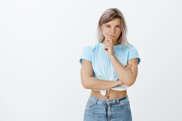 Portrait de jeune fille blonde intriguée qui pose en studio