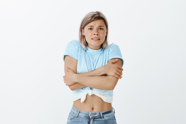 Portrait de jeune fille blonde timide qui pose en studio