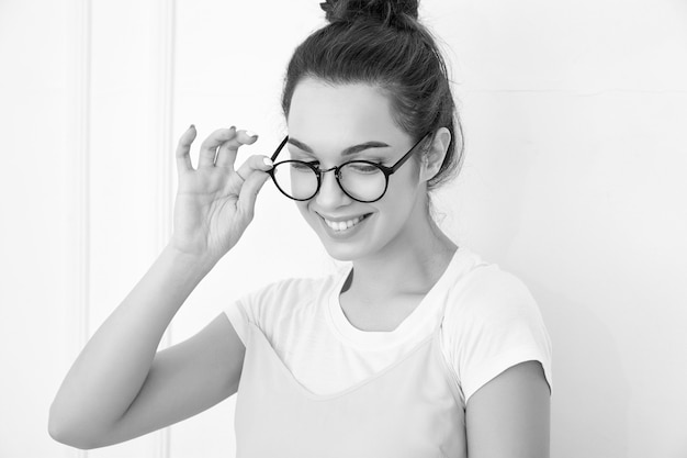 Portrait de jeune fille brune belle modèle de fille avec du maquillage nude dans des vêtements de hipster rose d'été coloré posant près du mur. regardant joyeusement