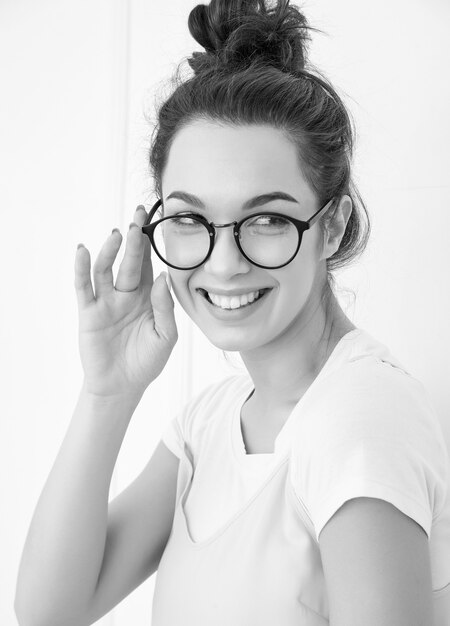 Portrait de jeune fille brune belle modèle de fille avec du maquillage nude dans des vêtements de hipster rose d'été coloré posant près du mur.