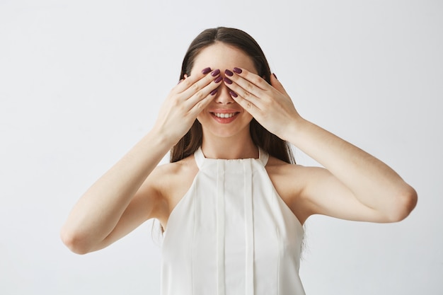 Portrait De Jeune Fille Brune Couvrant Les Yeux Avec Les Mains En Souriant.