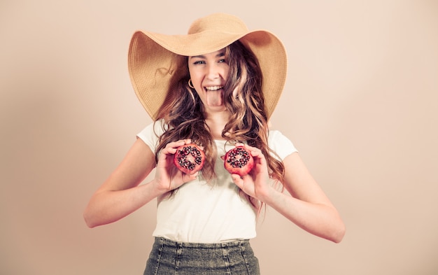 Portrait d'une jeune fille dans un chapeau d'été avec des fruits sur un fond coloré