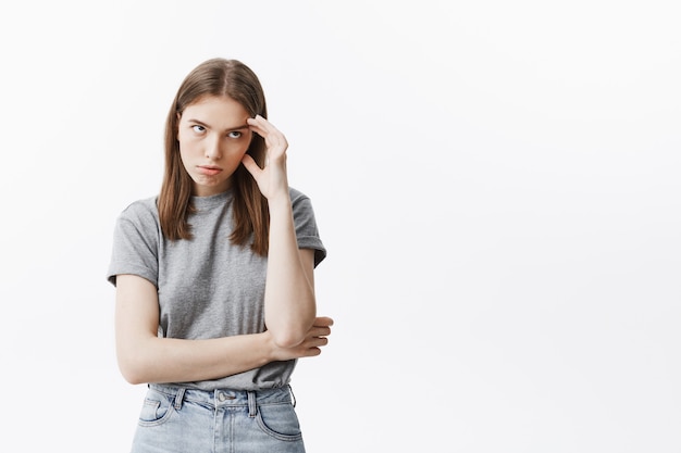 Portrait De Jeune Fille étudiante Caucasienne à La Mode Avec Des Cheveux Noirs En Tenue à La Mode, Massant Le Front Avec La Main, Regardant De Côté étant énervé Maman Enseignant Ses Choses élémentaires.