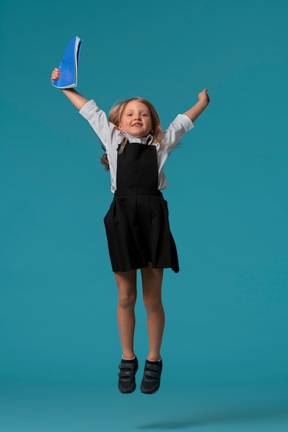 Photo gratuite portrait de jeune fille étudiante en uniforme scolaire sautant en l'air