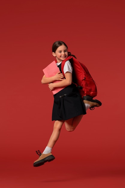 Photo gratuite portrait de jeune fille étudiante en uniforme scolaire sautant en l'air