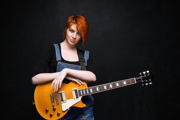 Portrait de jeune fille avec guitare sur fond noir.