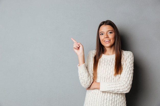 Portrait D'une Jeune Fille Heureuse En Pull Pointant Le Doigt