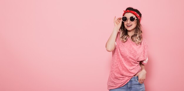 Portrait de jeune fille hipster dans des verres sur le mur rose