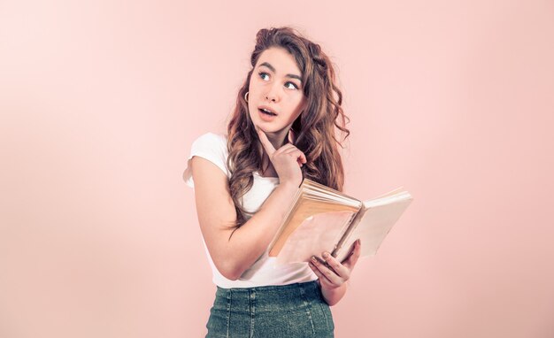 Portrait d'une jeune fille avec un livre sur un mur coloré