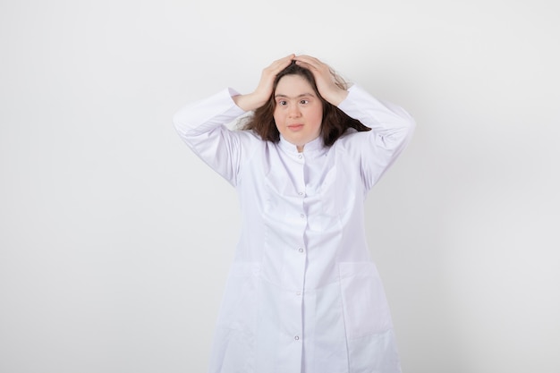 Portrait d'une jeune fille modèle trisomique debout avec un uniforme blanc.