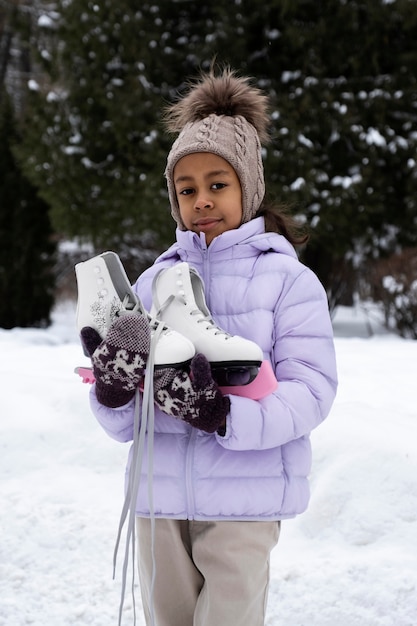 Portrait de jeune fille avec des patins à glace à l'extérieur en hiver