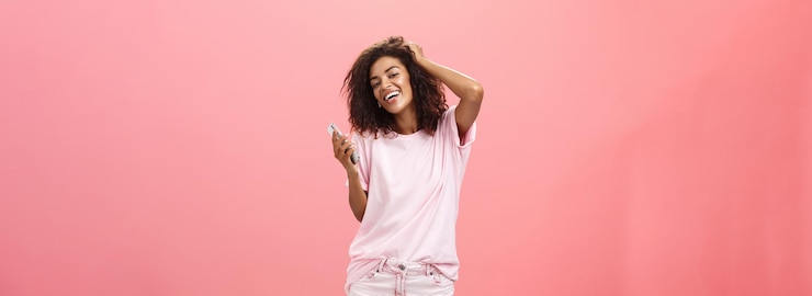 Photo gratuit portrait d'une jeune fille à la peau sombre moderne et insouciante utilisant un smartphone qui traîne joyeusement