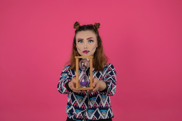 Photo gratuite portrait de jeune fille portant un maquillage fantaisie coloré et tenant du sable et une horloge. photo de haute qualité