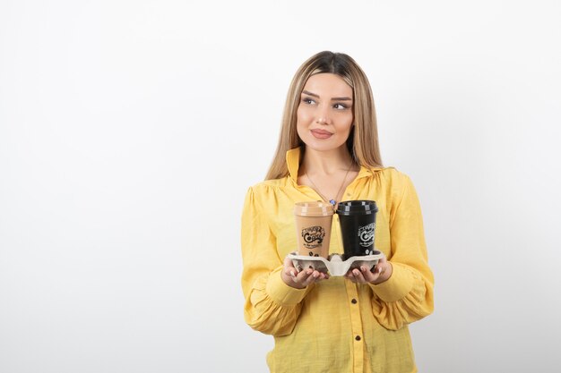 Portrait de jeune fille posant avec des tasses de café sur blanc.