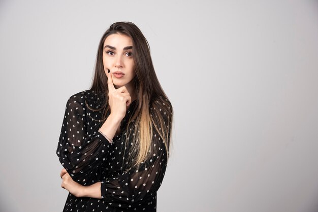 Portrait de jeune fille réfléchie tenant les mains sur la tête.