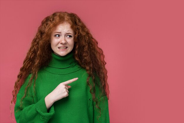 Portrait de jeune fille semblant confuse et pointant vers la gauche