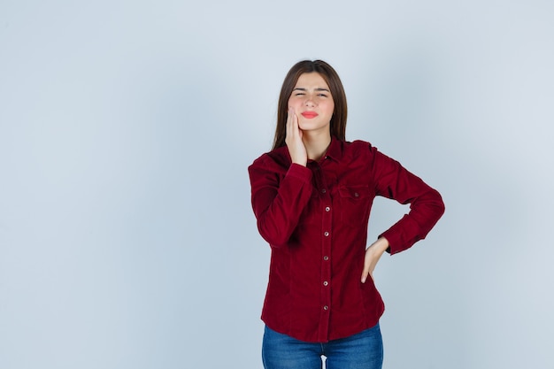 Portrait de jeune fille souffrant de maux de dents en chemisier bordeaux et à la malaise