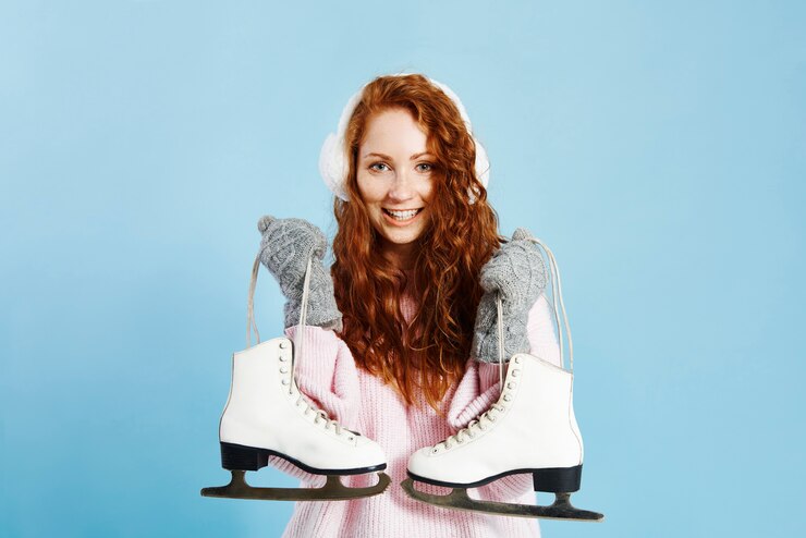 Photo gratuit portrait de jeune fille souriante tenant des patins à glace