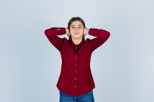 Portrait de jeune fille tenant les mains sur les oreilles en chemise décontractée et à la peur