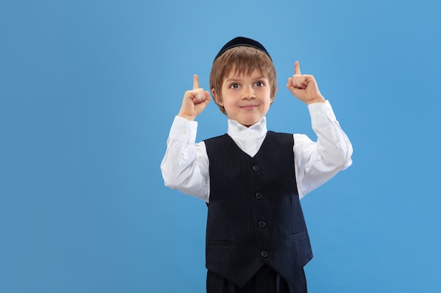 Portrait d'un jeune garçon juif orthodoxe isolé sur studio bleu