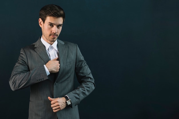 Portrait de jeune homme d&#39;affaires en costume debout sur fond noir