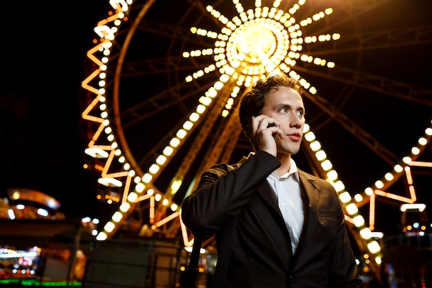 Portrait de jeune homme d'affaires prospère sur parc d'attractions de nuit. DOF peu profond