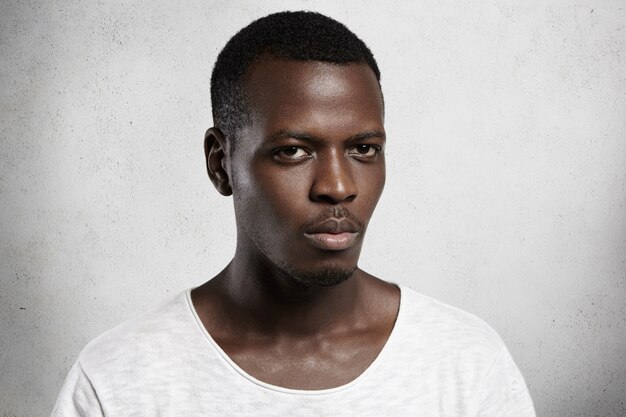 Portrait de jeune homme africain confiant et beau habillé avec désinvolture avec une expression de visage grave ou en colère.