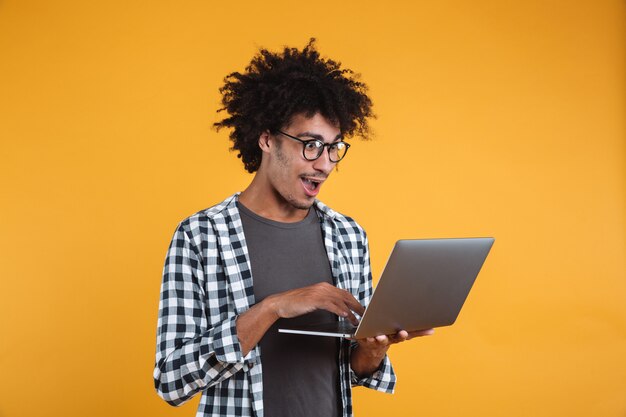 Portrait d'un jeune homme africain excité à lunettes