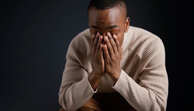 Portrait jeune homme africain avec les mains couvrant le visage