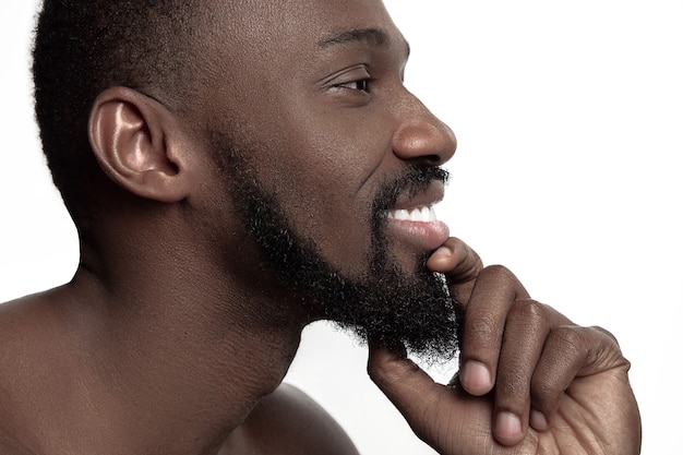 Portrait d'un jeune homme africain souriant heureux nu au studio. Modèle masculin de haute couture posant et isolé sur fond blanc