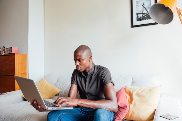Portrait d&#39;un jeune homme africain utilisant un ordinateur portable à la maison