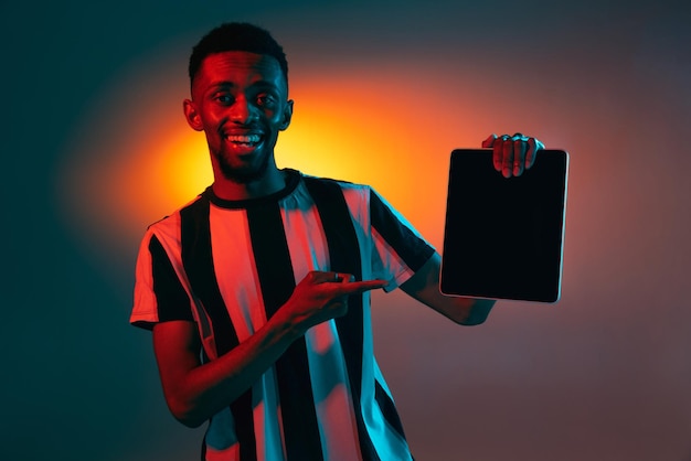 Portrait de jeune homme afro-américain sur fond de studio rouge au néon Concept d'émotions humaines expression faciale annonce de vente pour les jeunes