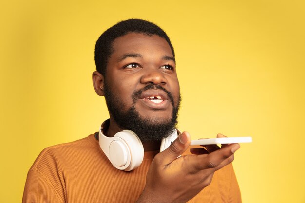 Portrait d'un jeune homme afro-américain isolé sur une expression faciale jaune.