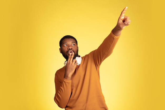 Portrait d'un jeune homme afro-américain isolé sur une expression faciale jaune.